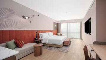 Una habitación de hotel moderna con cama, sofá, escritorio y televisor.