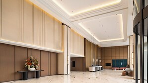 Un hall d’entrée spacieux comprenant un comptoir d’accueil, un espace salon et un grand mur revêtu de panneaux verticaux.