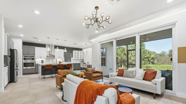 A modern kitchen with stainless steel appliances, a dining area with a white table and chairs, and a large window offering a view of greenery. - Palm Bay Luxury Haven (Palm Bay)