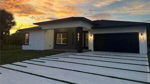 A modern two-story house with a garage, a driveway with a unique striped pattern, and a well-lit entrance. - Palm Bay Luxury Haven (Palm Bay)