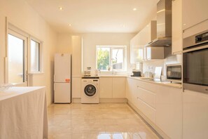 Eine moderne Küche mit Einbauwaschmaschine, Kühlschrank und Mikrowelle.