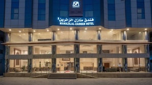 A hotel with a modern facade, large glass windows, and a prominent entrance with steps. - Manazel Alzaereen Hotel 2 (Makkah)