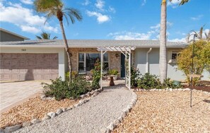 A residential property with a garage, a covered porch, and a gravel driveway. - Jefferson Beach Escape (Fort Myers Beach)