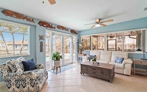 A spacious living room with a ceiling fan, a sofa, a coffee table, and a dining area with a table and chairs. - Jefferson Beach Escape (Fort Myers Beach)