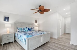 A bedroom with a bed, nightstands, a ceiling fan, and a wooden floor. - Clear Day - Luxury on the Water (Fort Myers Beach)
