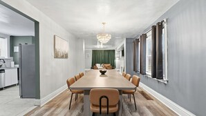 Comedor con una larga mesa de madera, sillas alrededor y una araña colgante.