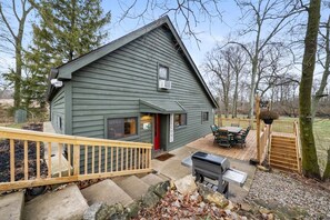 A green wooden house with a deck, a barbecue grill, and a welcome sign. - Pearl’s Place- a Creekside Cabin (Union Township)