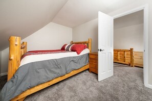 A bedroom with a wooden bed, a white door, and a wooden wardrobe. - Pearl’s Place- a Creekside Cabin (Union Township)