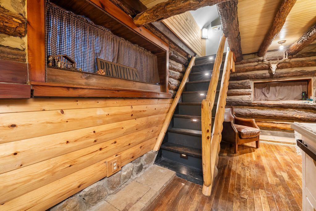 Eine Holztreppe führt zu einem Schlafbereich mit einem Schachfenster und rustikalem Interieur.