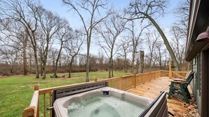 Un bain à remous sur une terrasse en bois, avec vue sur des arbres sans feuilles.
