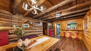 Un intérieur rustique avec des éléments en bois, notamment une table à manger en bois, des bougies et un lustre.