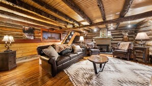 L’intérieur d’une cabane en rondins, avec un canapé en cuir, un plancher en bois et un décor rustique.
