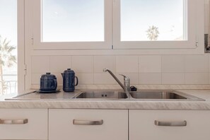 A kitchen with a double sink, two electric kettins, and a window with a view of palm trees. - CASA MEDITERRANEA - Vista Mare - Parcheggio (Sanremo)