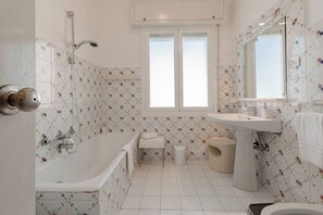 Ein Badezimmer mit Badewanne, Waschbecken, Toilette und einem Fenster.