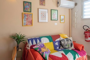 A room with a colorful bed, a potted plant, and wall-mounted artwork. - LA TERRAZZA SUL MARE - Sanremo (Sanremo)