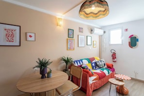 Een gezellige woonkamer met een bank, een eettafel en een hanglamp.