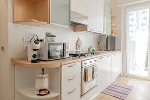 Eine moderne Küche mit weißen Schränken, einer eingebauten Mikrowelle, einem Toaster und einem Herd.