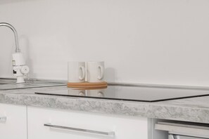 A kitchen with a white countertop, a stainless steel faucet, and two white mugs on a wooden coaster. - SEA LOFT - Vista Mare - Sanremo (Sanremo)