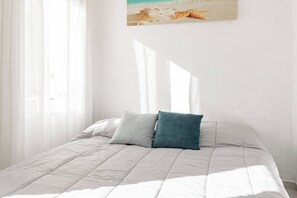 A bedroom with a bed, two pillows, a painting of a beach scene, and sheer curtains. - SEA LOFT - Vista Mare - Sanremo (Sanremo)