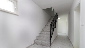 Eine Treppe mit weißen Marmorstufen und schwarzen Geländern, die zu einem Raum mit weißen Wänden und einem Fenster führt.