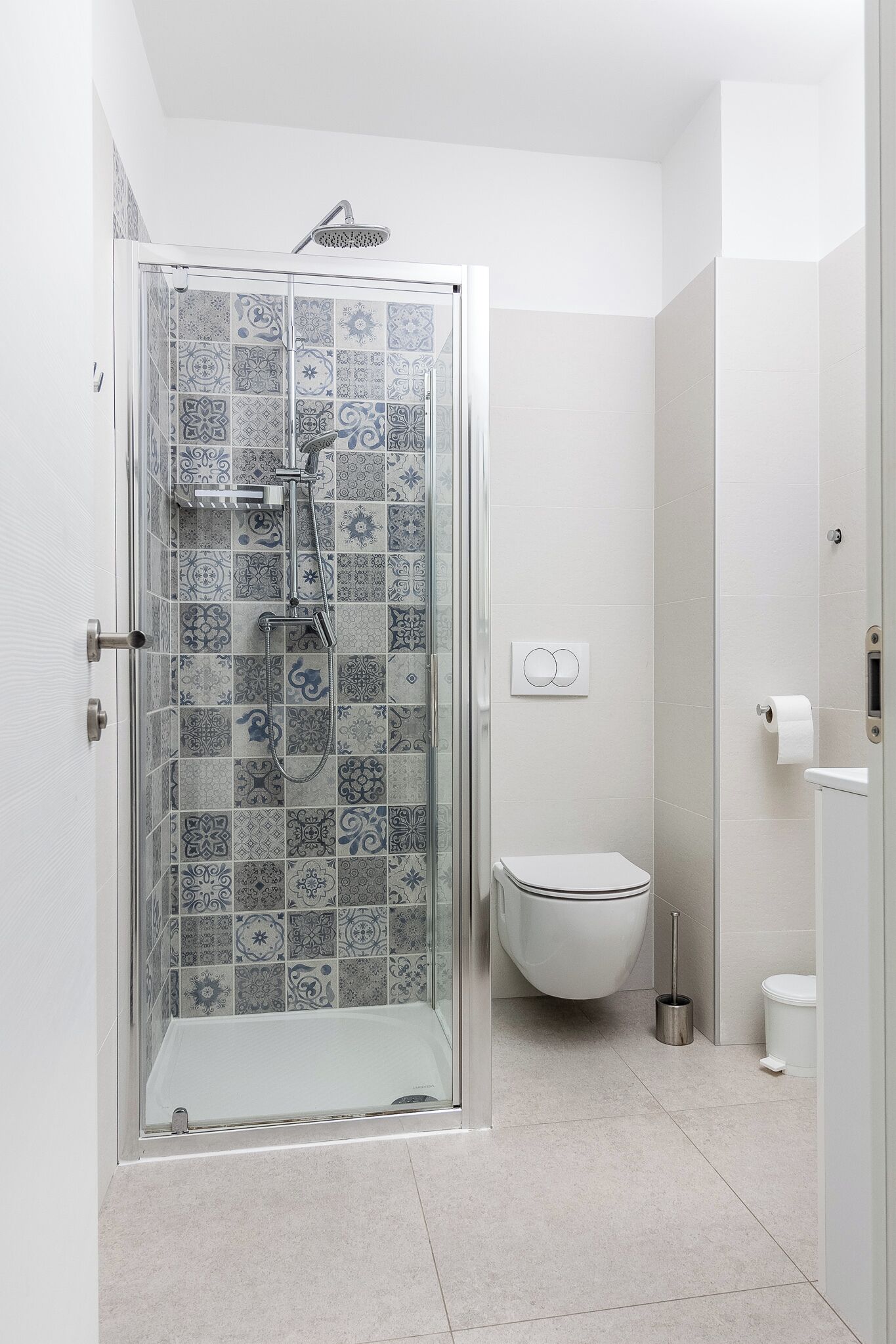 Un baño con ducha, inodoro y zona de ducha con mampara de vidrio.