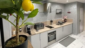 Een moderne keuken met grijze kastjes, een inbouwoven, een spoelbak en een koffieapparaat.