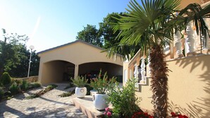Un bâtiment doté d’une entrée abritée, d’un palmier et de parterres de fleurs.