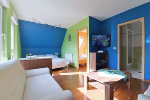 A modern room with a bed, a sofa, a TV, and a wooden table.