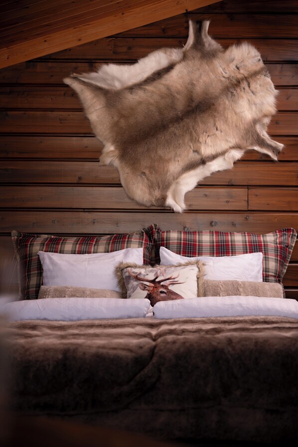 Ein Bett mit einem Fellüberwurf, Karo-Kissen und einem Kissen in Form eines Hirschkopfes.