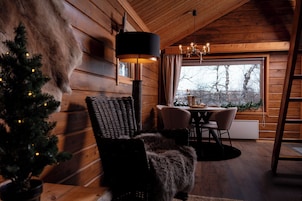 Interior acogedor de una cabaña con detalles de madera, un comedor, un árbol de Navidad y un ventanal grande.