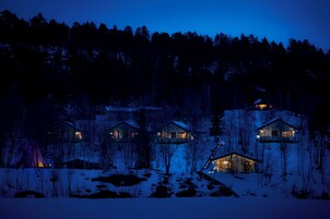 Um conjunto de cabanas em uma floresta nevada à noite.