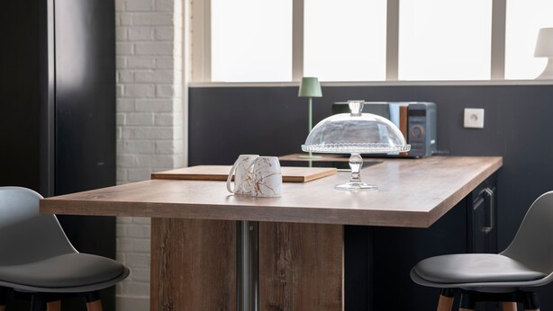 Een moderne keuken met een houten tafel, twee stoelen, een koffiezetapparaat, een glazen taatsdeksel en een radio.
