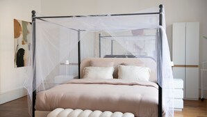 Een slaapkamer met een hemelbed, nachtkastje en een kledingkast.