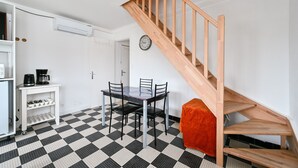 Ein Essbereich mit Schachbrettboden, einer Holztreppe und einem Esstisch mit Stühlen.