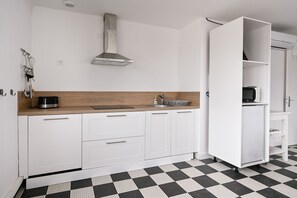 Eine moderne Küche mit weißen Schränken, einem schwarz-weißen Schachbrettboden und einem eingebauten Backofen.