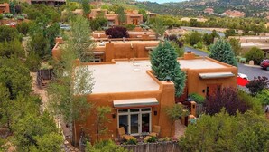 A residential area with stucco houses, a paved driveway, and a parking area. - Luxury Adobe Retreat with Jemez Mountain Views (Santa Fe)