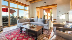 A spacious living room with a large sofa, a coffee table, and a leather armchair. - Luxury Adobe Retreat with Jemez Mountain Views (Santa Fe)