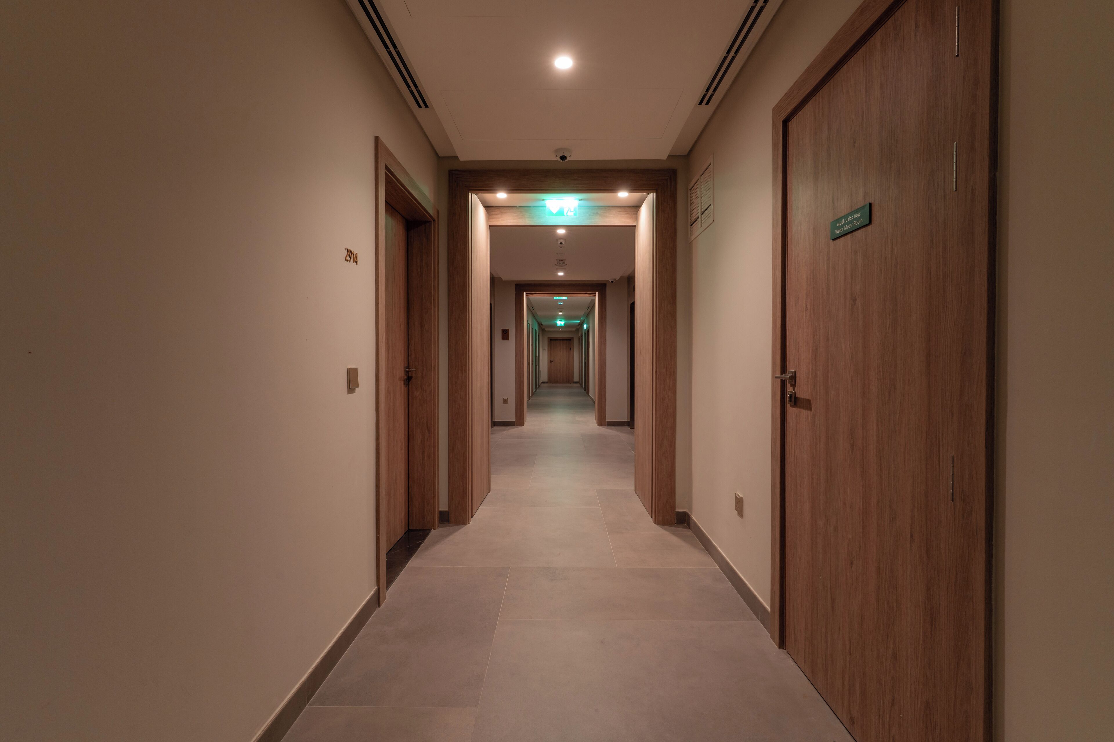 A hotel corridor with wooden doors and a tiled floor.