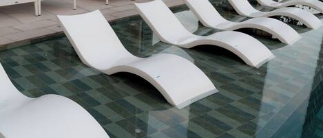 A poolside area with white lounge chairs arranged in rows.