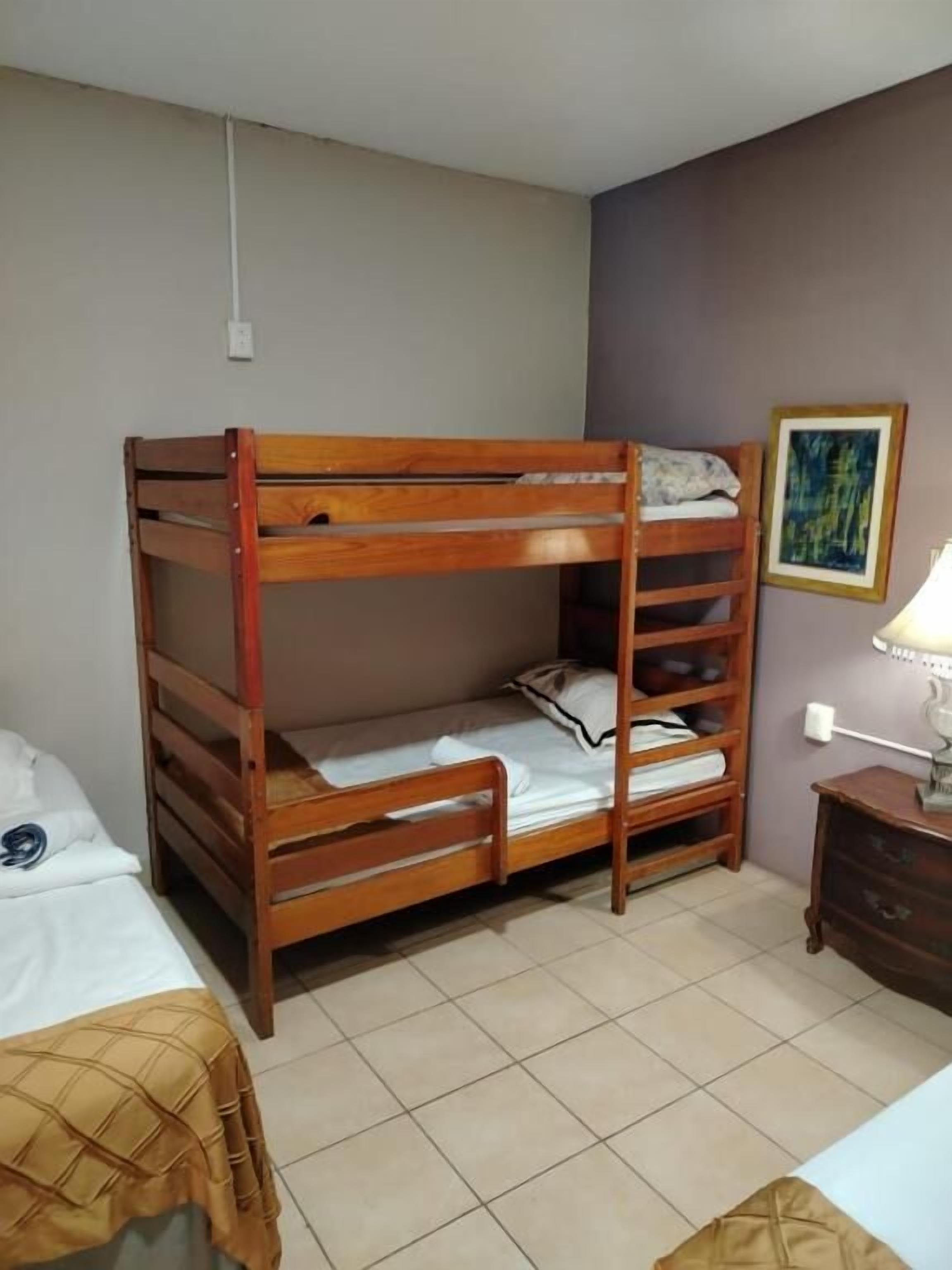 A bunk bed room with a small bedside table and a lamp.