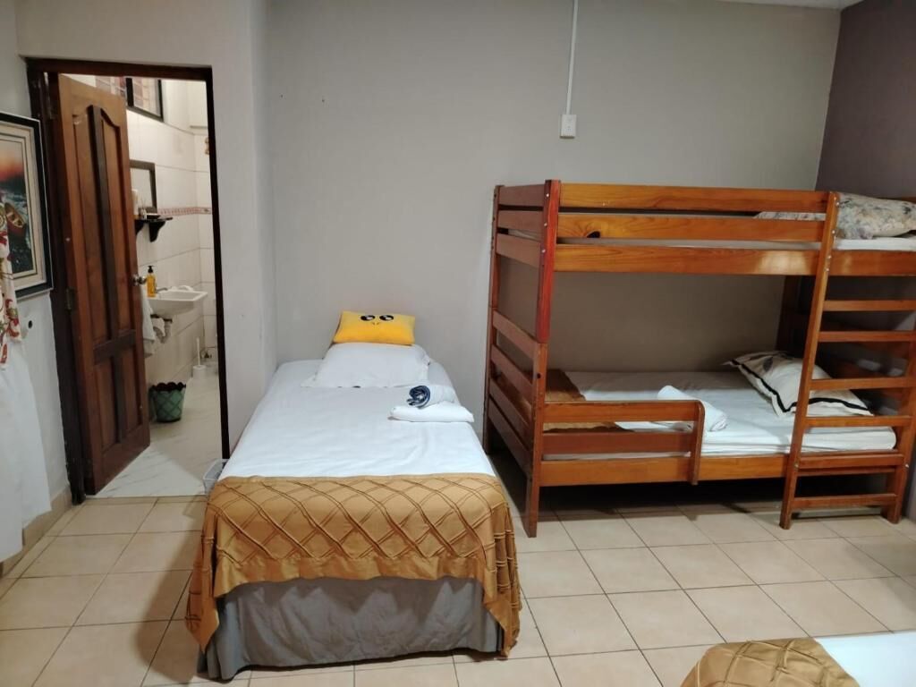 A bedroom with a single bed, a bunk bed, and a door leading to a bathroom.