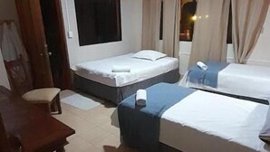 Een hotelkamer met twee eenpersoonsbedden, een houten stoel, een bureau en een televisie.