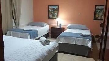 A hotel room with two beds, a nightstand, a lamp, and a small rug.