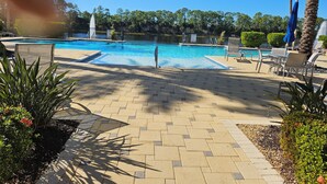 A swimming pool with a tiled deck, lounge chairs, and palm trees. - Cozy 2-bedroom condo with AC in fabulous Naples (Naples)