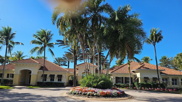 A hotel with a paved courtyard, palm trees, and a flower bed. - Cozy 2-bedroom condo with AC in fabulous Naples (Naples)
