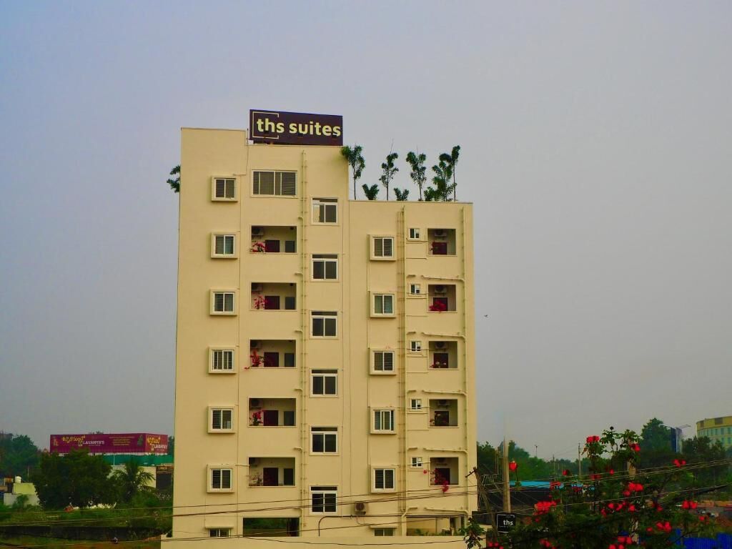A multi-story hotel with a sign reading "th's suites" on the top.