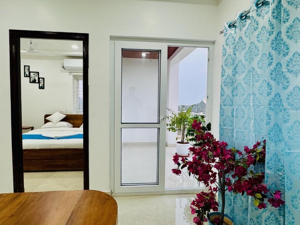 A room with a bed, a sliding door, a potted plant, and a curtain.