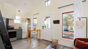 Un espacio habitable compacto con kitchenette, comedor y zona de estar con sofá y mesa de centro.