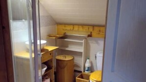 Un baño pequeño y funcional con inodoro, lavamanos y estantes para guardar objetos.