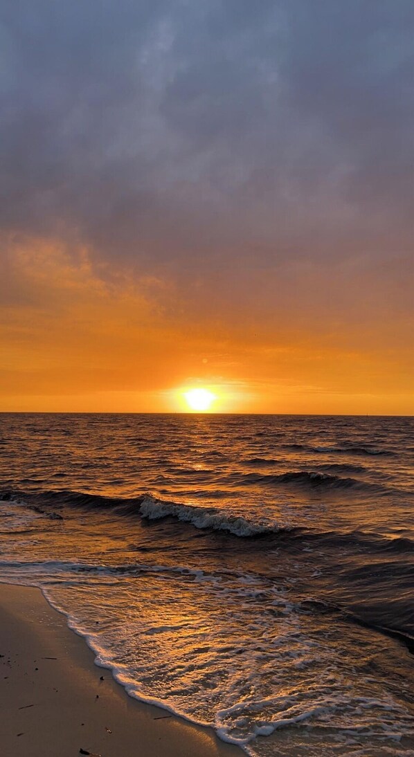 Una playa con olas y un atardecer.